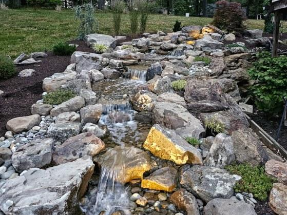 Natural stone waterfall feature set into a planted slope