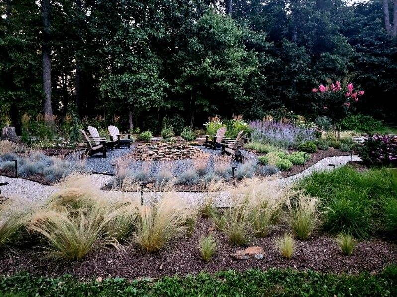 Designed garden with ornamental grasses, a gravel path, path lights and a seating area