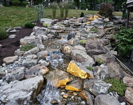 Stone waterfall and stream cascading through boulders and river rock